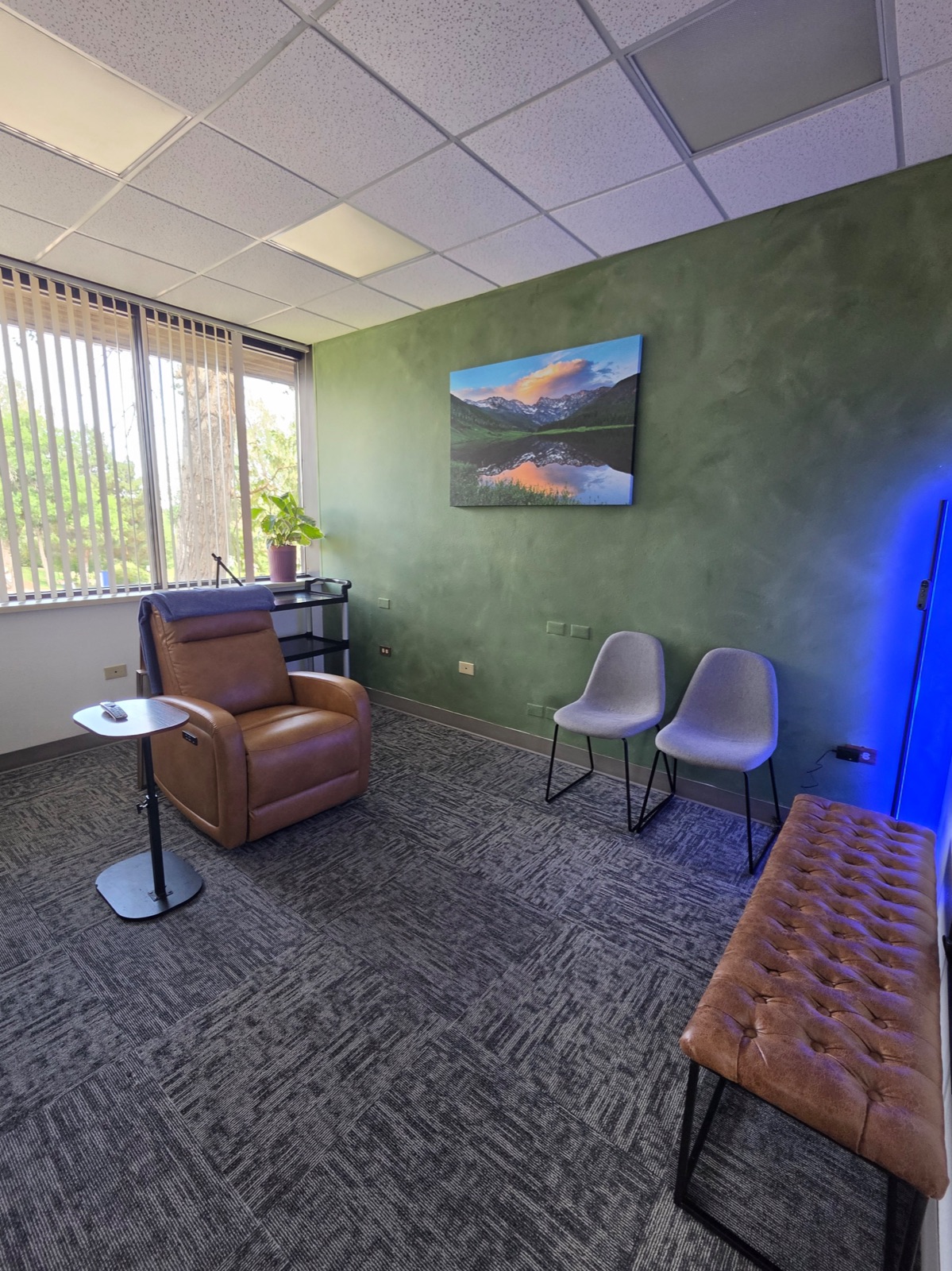 TMS treatment room at Fortifying Wellness in Littleton with a reclining chair, Colorado mountain artwork, and natural light